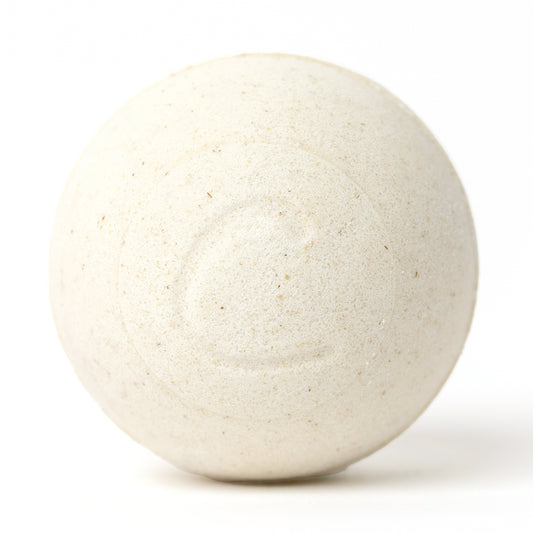 Round, cream-colored oatmeal bath bomb with a textured, speckled surface and a subtle embossed letter C on a white background.