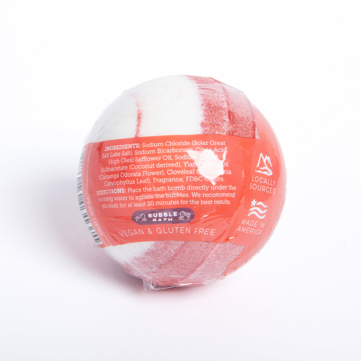 Round Hibiscus Passion bath bomb with red and white swirls, wrapped in clear plastic with printed ingredient information.